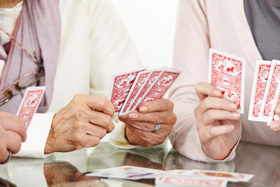 Senior and two other people playing cards.