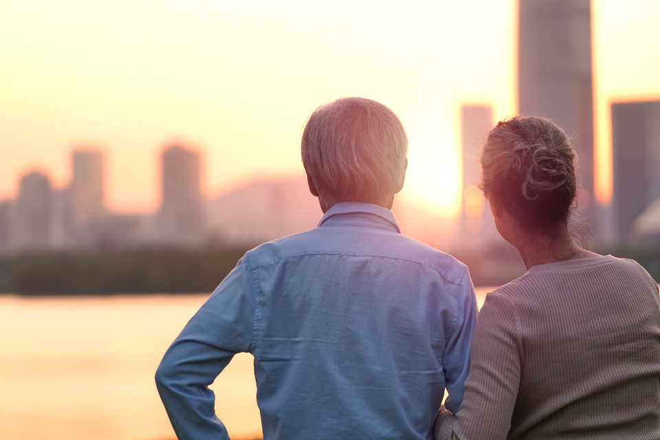 Elderly man with his daughter looking at sunset over a skyline