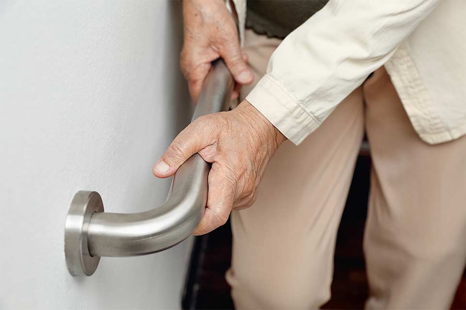 Elderly woman using a handrail to prevent an unexpected fall.