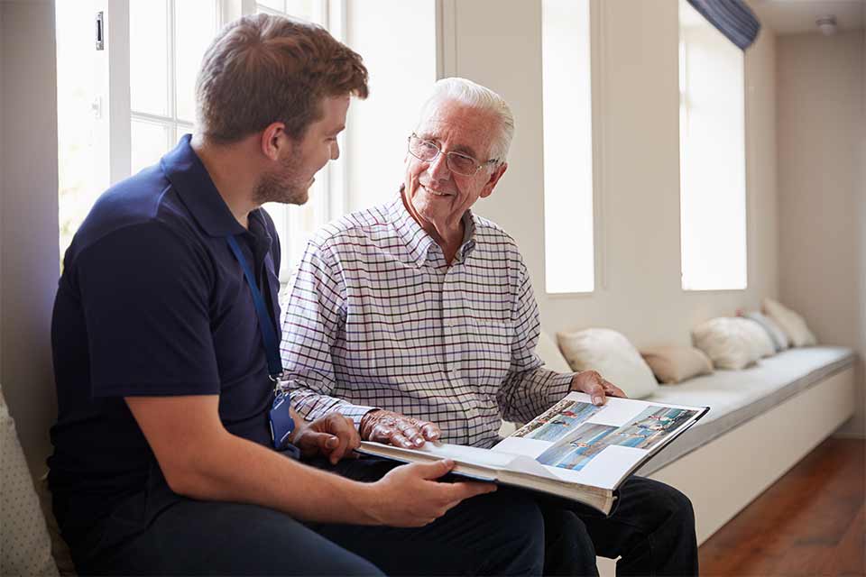 Elderly man and his grandson looking at a photo album.