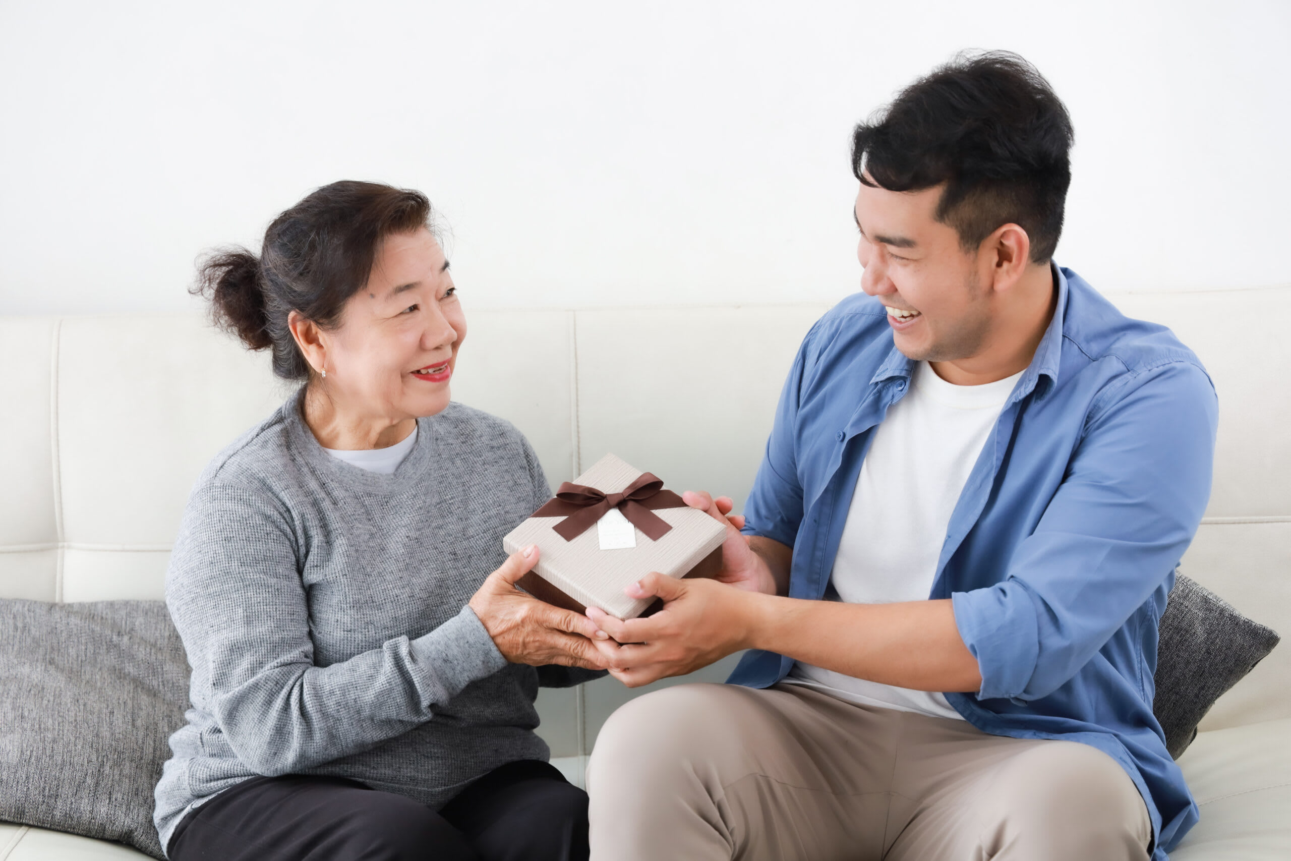 A young man giving a gift to a senior woman