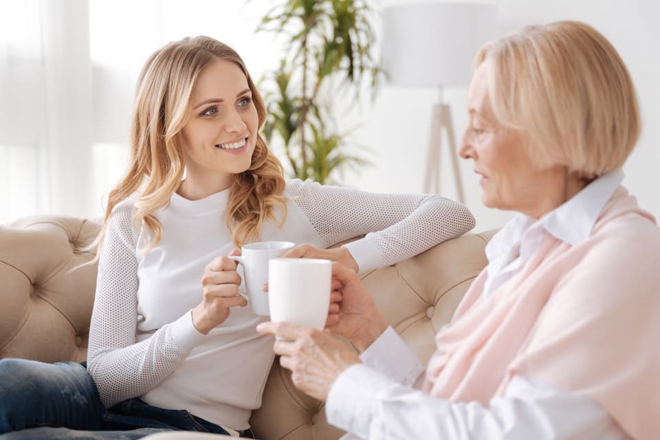 Younger and older woman sitting on couch talking.