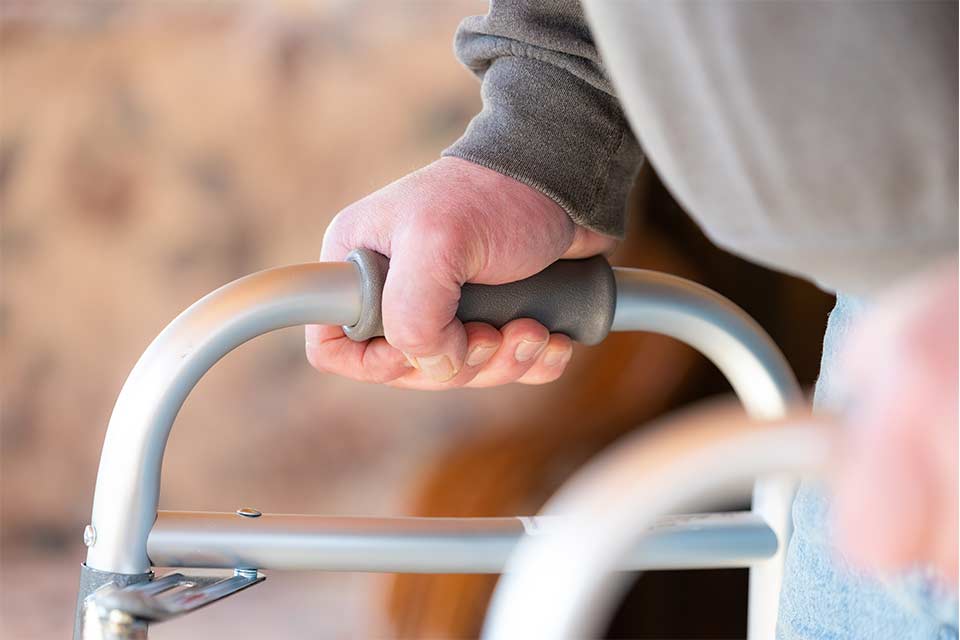 Elderly man using a walker after undergoing a hip replacement.