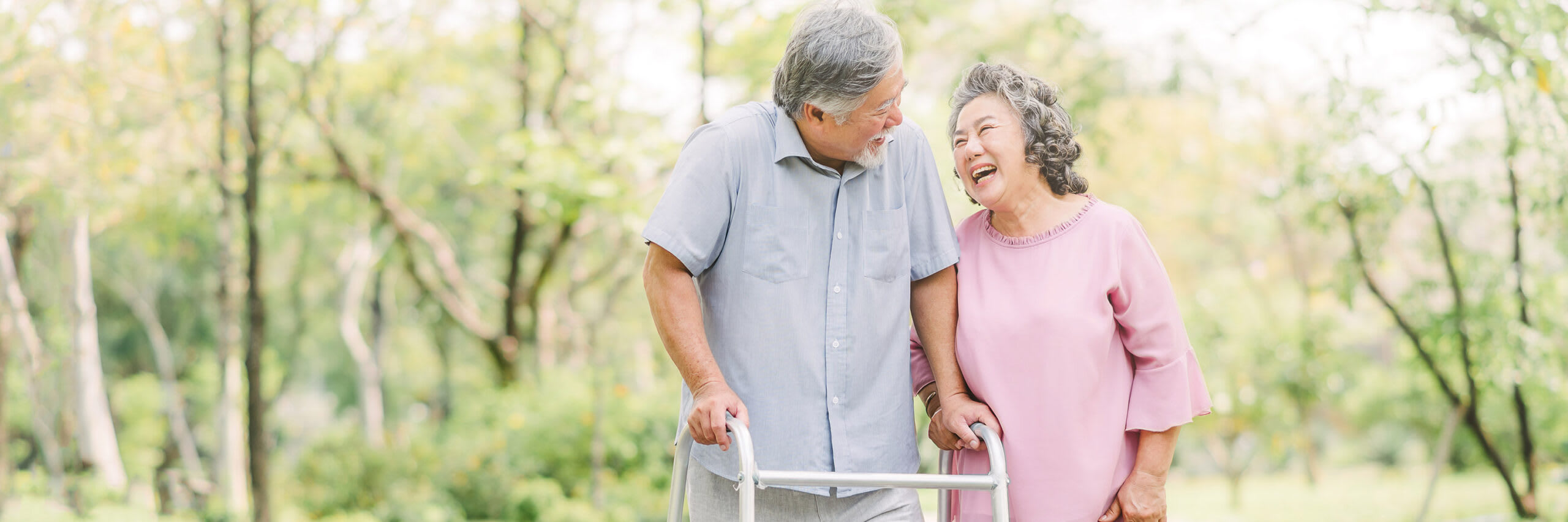 A senior couple outside in pleasant conversation while one uses a walker