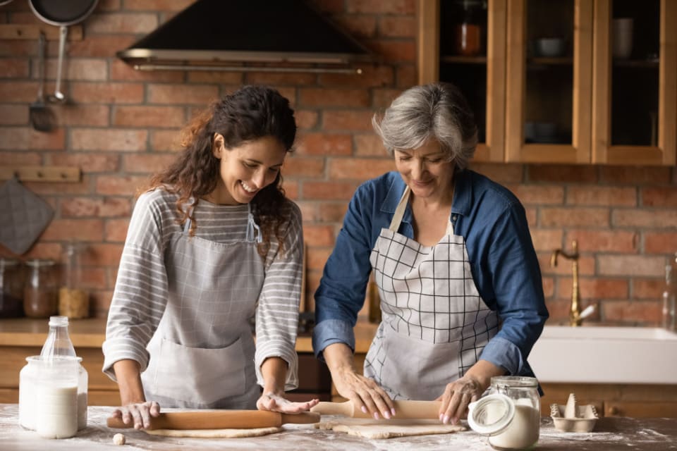 A senior woman and a middle-aged woman baking together in a kitchen