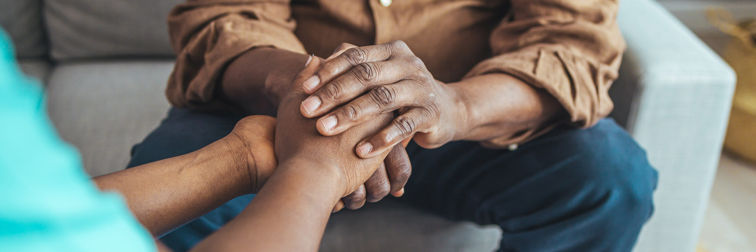 A closeup of a senior's hands holding the hands of a caregiver