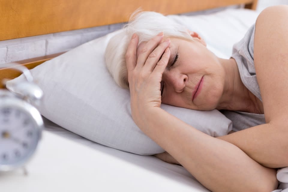 A senior woman sleeping next to an alarm clock