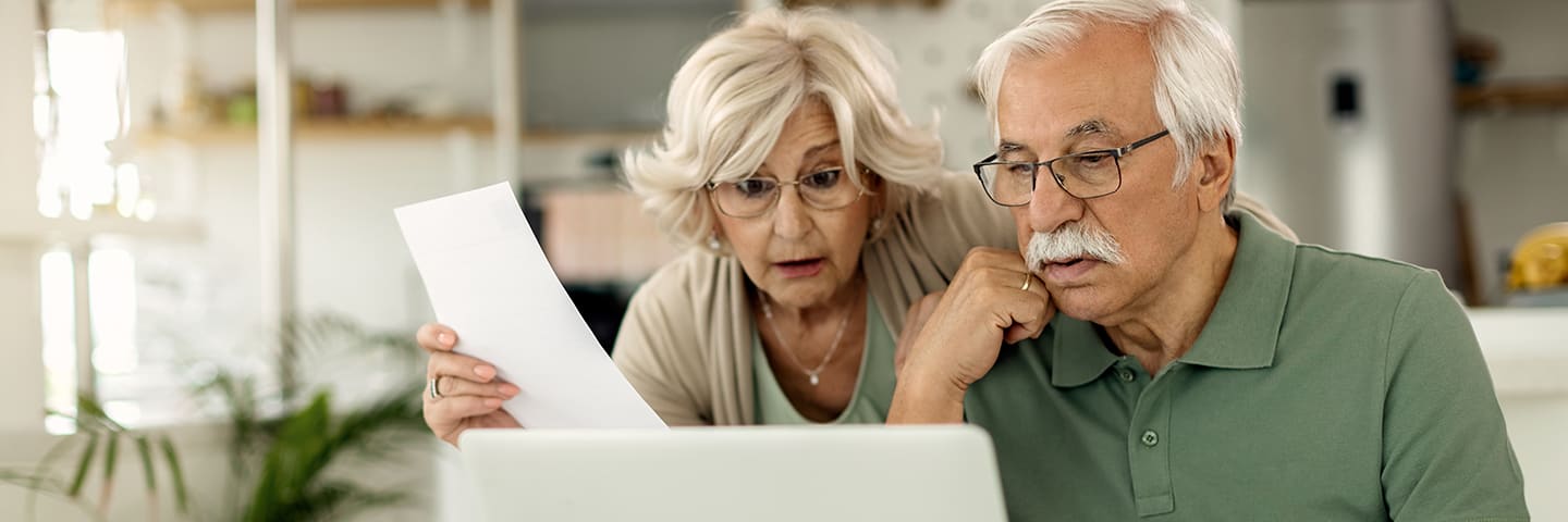 Seniors looking at computer and paperwork together