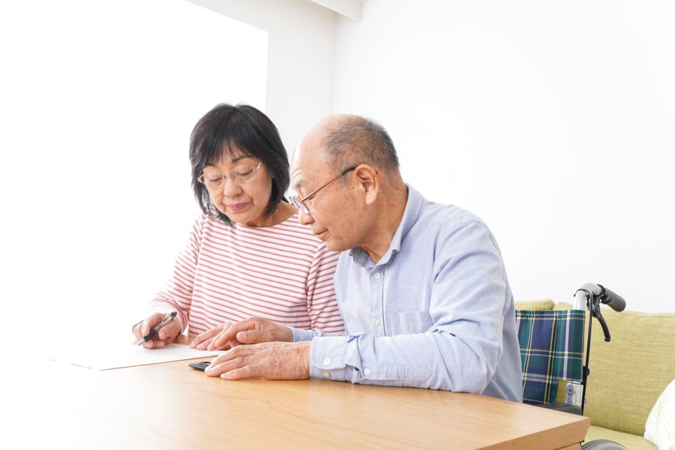 A senior man and woman sit at a table while looking at a document.
