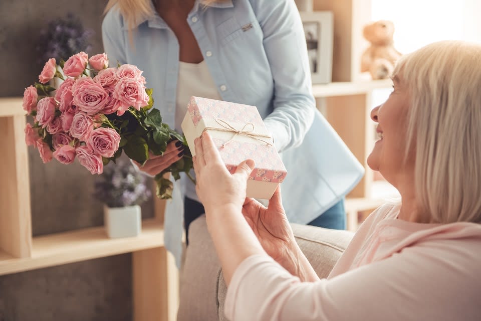 Woman in blue shirt giving gift to older woman