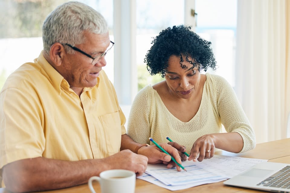 A senior couple makes a budget at their kitchen table.