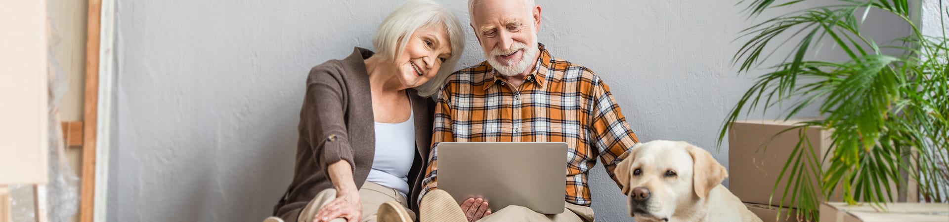 A senior couple researches home care on a tablet while their dog sits nearby