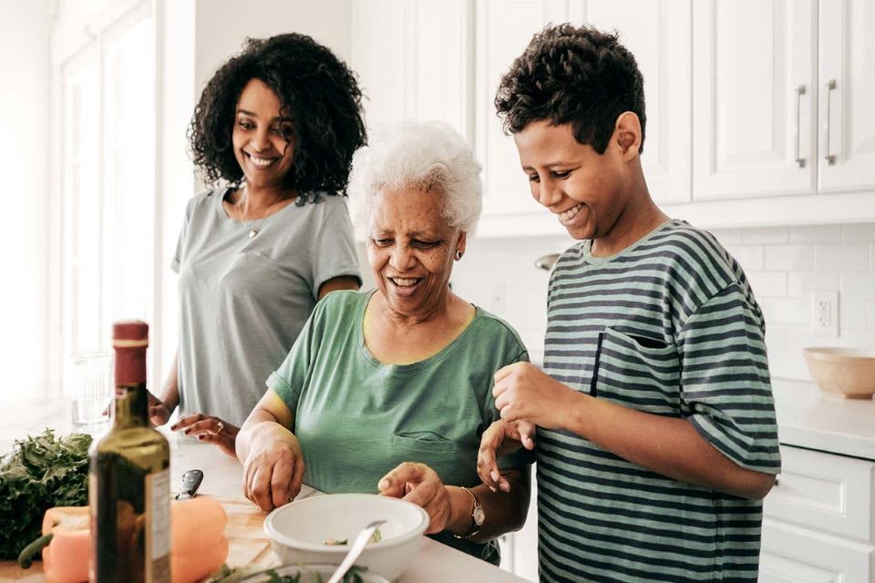 A senior woman cooks a meal with her family.