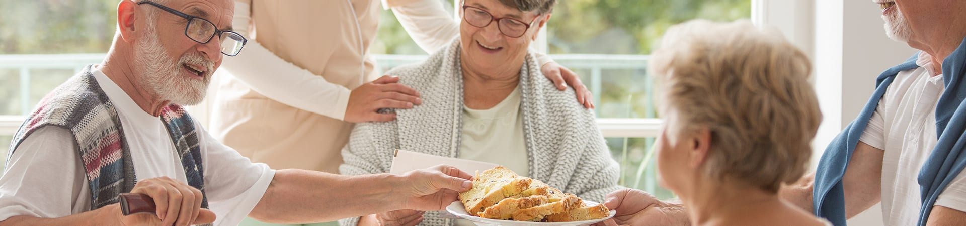 A group of seniors converse around an assisted living dining table