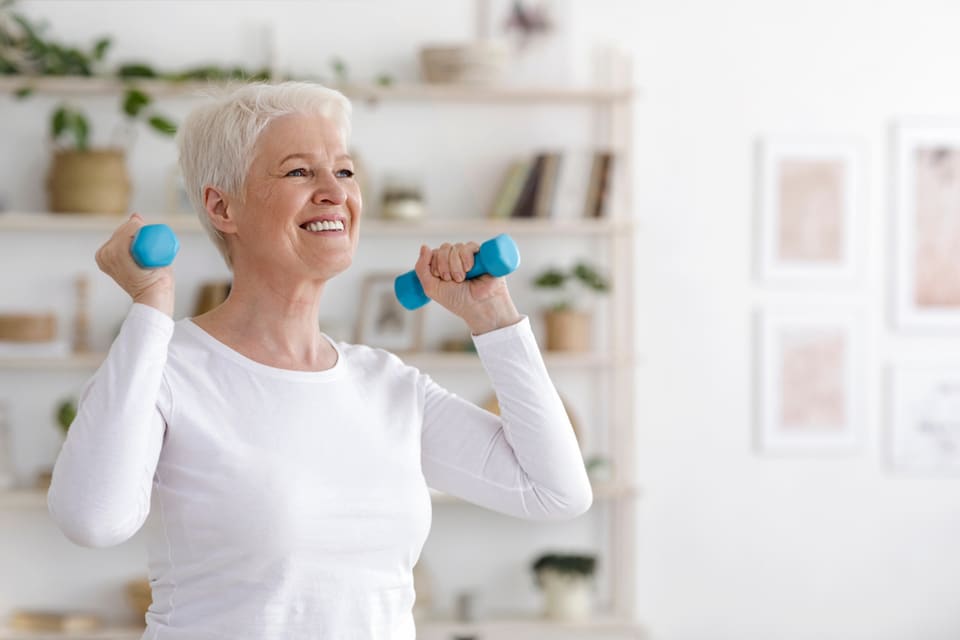 A senior woman exercises with dumbells.