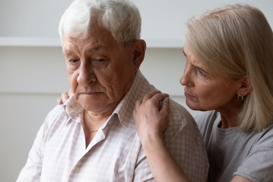 A senior man is comforted by his daughter.