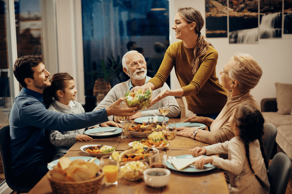 A family passes around food at a dinner table.