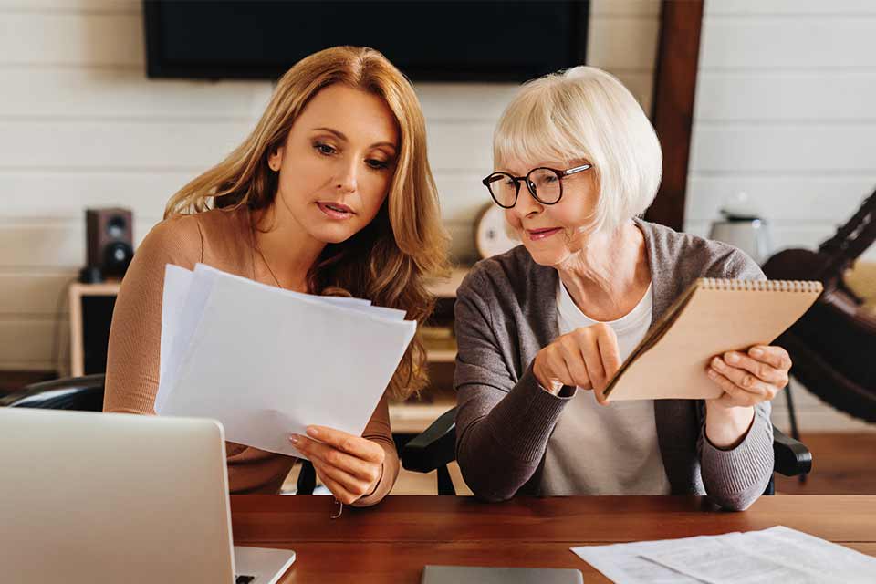 Elderly woman receiving savvy financial advice from her daughter.