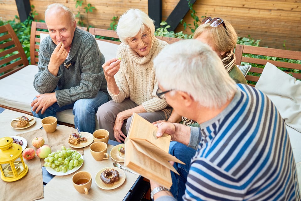 Group of seniors gathered around a table eating and playing games.